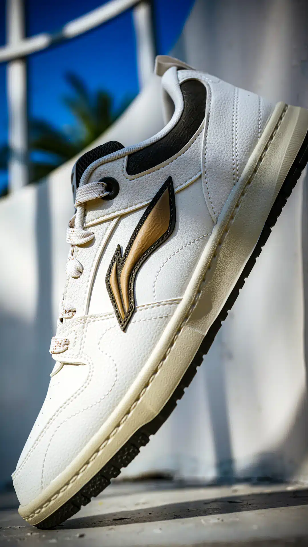 A white sneaker with gold accents against a blue sky.