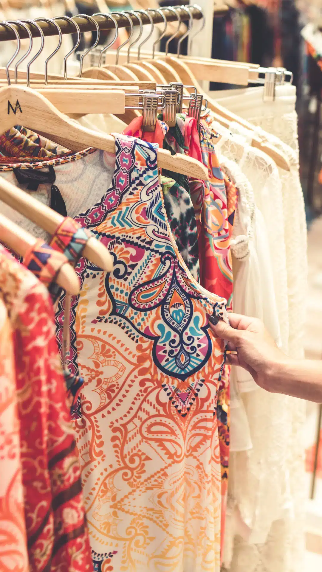 a woman is trying to find a dress on a rack
