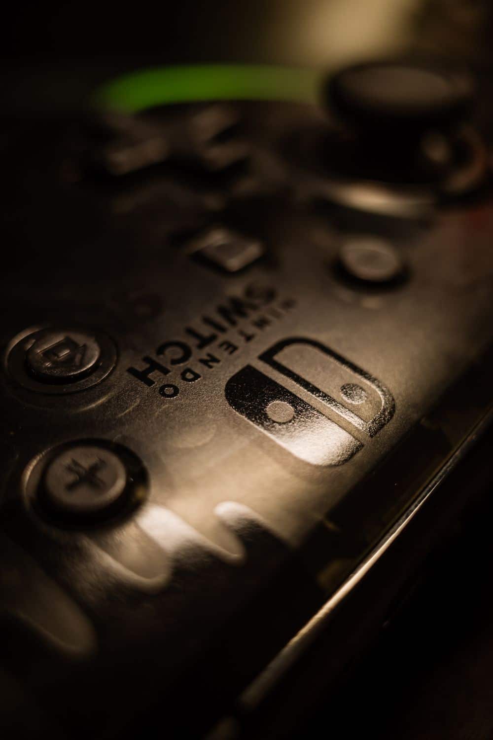 Macro shot of a vintage game controller reflecting light, highlighting analog buttons and intricate details.