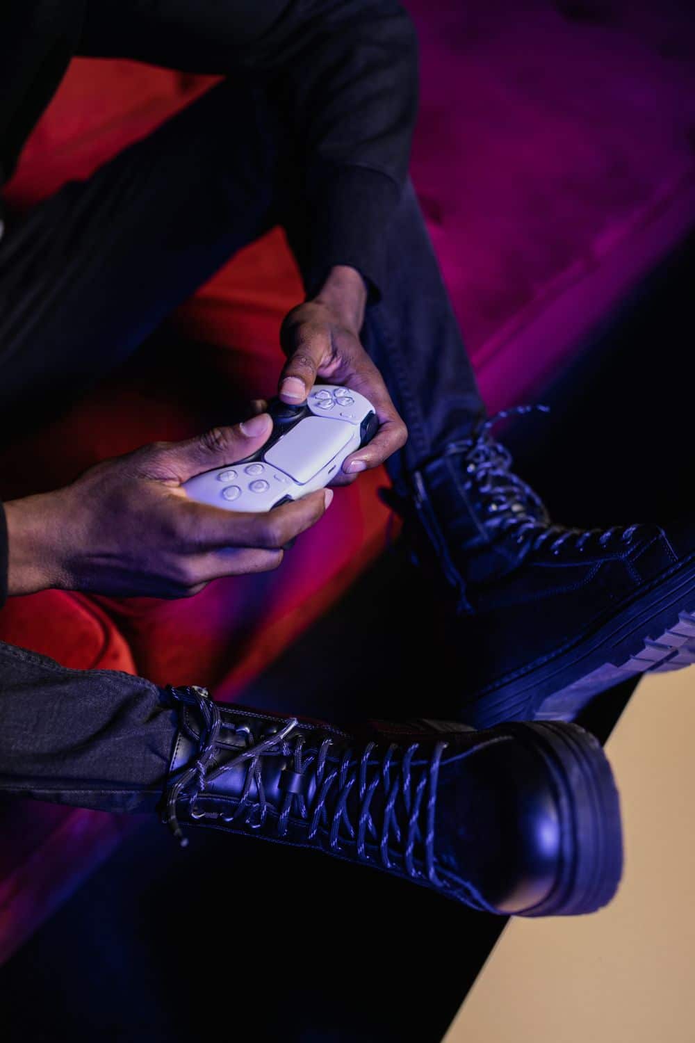 Person holding a game controller, wearing leather boots. Perfect stock photo for gaming and lifestyle content.