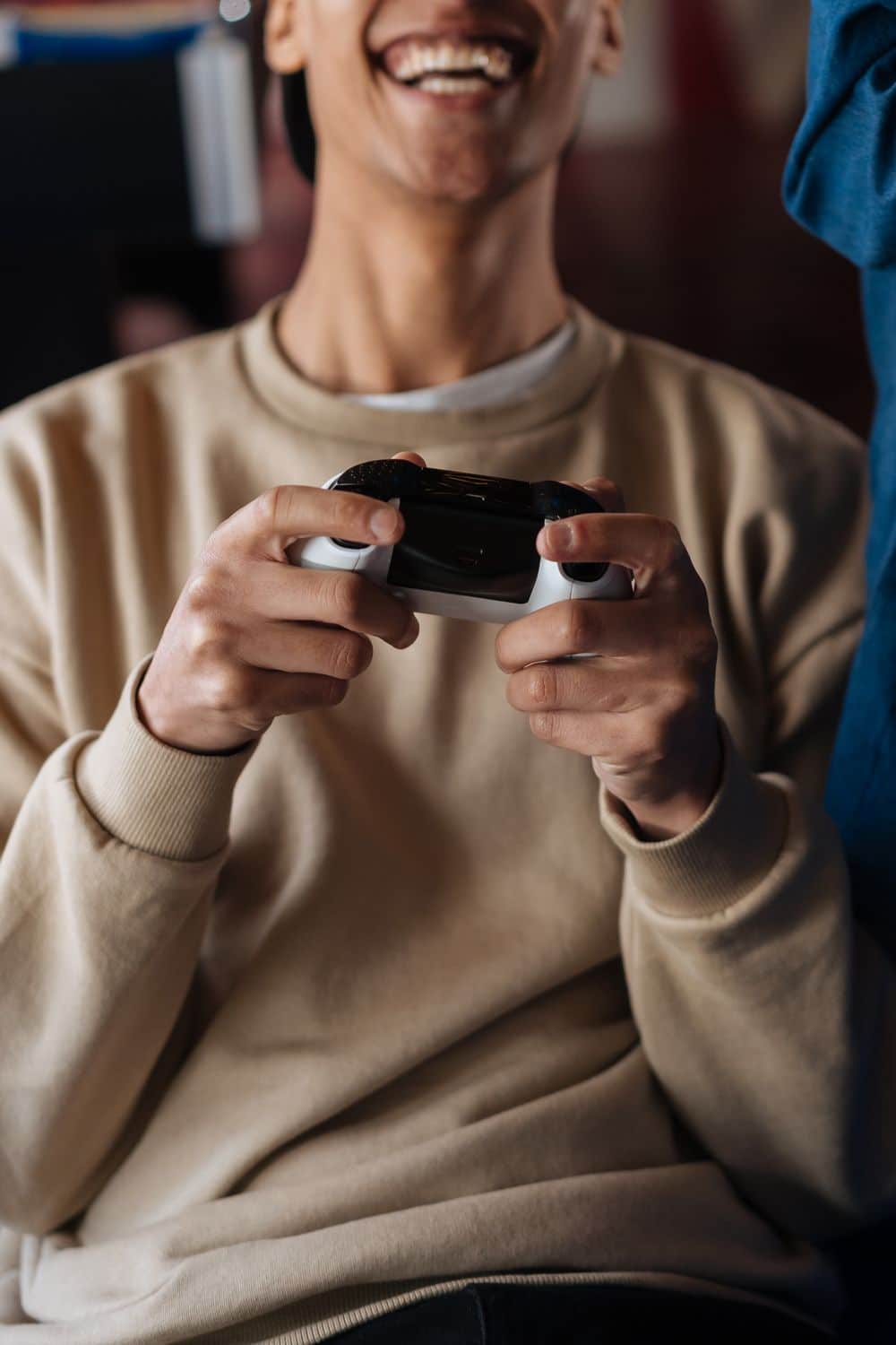 Smiling young adult male holding a game controller, immersed in a video game indoors.